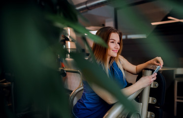 A portrait of young girl or woman with smartphone in a gym.