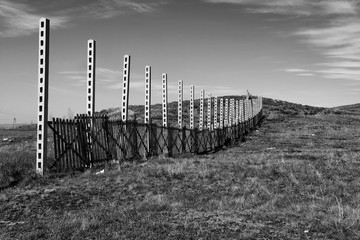 Fence in field. Steppe landscape. Monochrome.