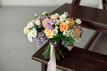 Wedding bouquet of pink roses with a lilac on a blurred background on a wooden staircase