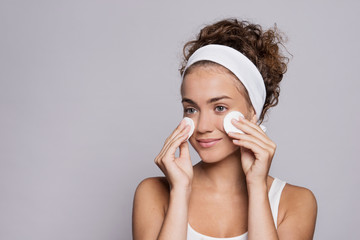 Portrait of a young woman cleaning face in a studio, beauty and skin care.