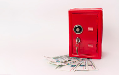 red safe on a fan of russian money on white background. bank with key.