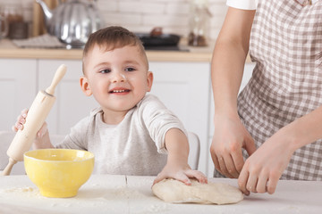 Cute child cooking. Adorable kid kneading the dough. Baby on the kitchen.