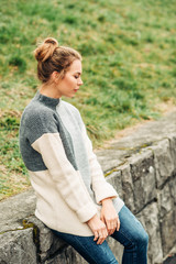 Outdoor portrait of young pretty woman wearing grey warm high neck pullover, cold weather