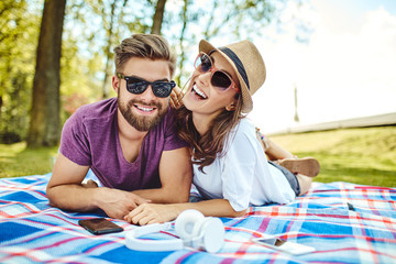 Happy couple lying on a blanket in the park during summer