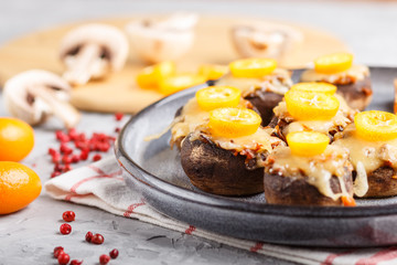 stuffed fried champignons with cheese, kumquats and green peas on a gray concrete background. side view, close up, macro.
