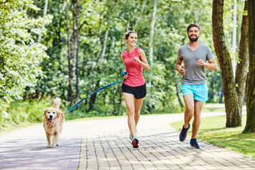 Happy couple running with dog in park