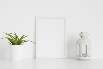 White frame mockup with a succulent plant and a candle holder on a white table. Portrait orientation.