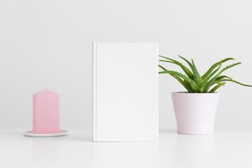 White book mockup with a succulent plant and a candle on a white table.
