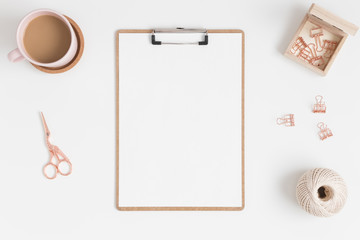 Top view of a wooden clipboard mockup with a coffee and workspace accessories on a white table.