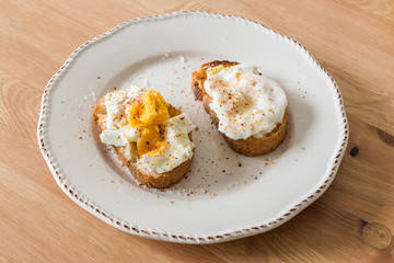 Homemade Poached Eggs with Spices and Bread on Wooden Surface usually served with Coffee