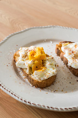 Homemade Poached Eggs with Spices and Bread on Wooden Surface usually served with Coffee
