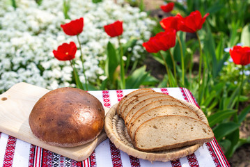 Rye bread on a wooden board against the background of spring flowers. fresh bread on a background...
