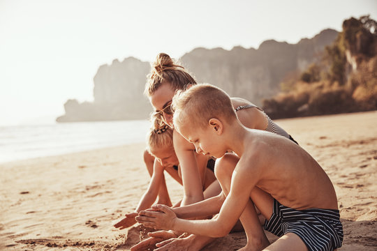 Mother and children building sandcastles together at the beach