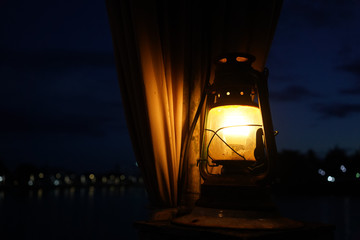 candles in the lantern in the dark with the background of a curtain and the bokeh of the light from the city