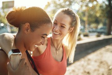 Two friends in sportswear laughing after an outdoor workout toge - Powered by Adobe