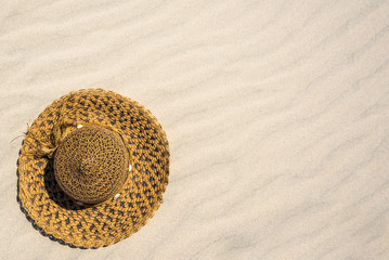 Fototapeta na wymiar Beach accessory on sand - hat for sun protection. Summer vacation, flat lay background.
