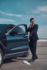 I will be in time! Full length of handsome young businessman talking on the phone while entering...