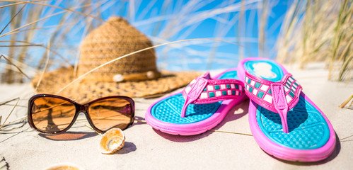 Background with vacation accessories on the beach - sunglasses hat and flip flop on sand. Summer...