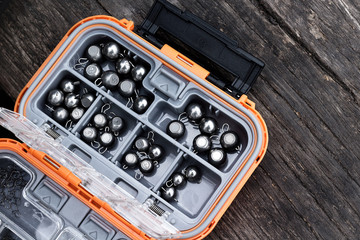 Fishing box filled with tungsten sinkers on the wooden table.