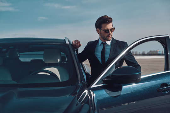 Luxury style. Handsome young businessman entering his car while standing outdoors