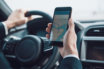Searching for the shortest way. Close up of young man using smart phone to check the map while...