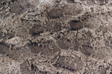 Fototapeta na wymiar Dirty tracks of snow on asphalt. The footprints of shoes on a dirty snow. Bad ecology, dirty snow.