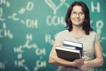 Mature woman teacher with books on background