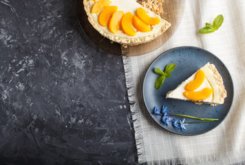 A piece of peach cheesecake on a blue ceramic plate with blue flowers on a black concrete background. top view, copy space.
