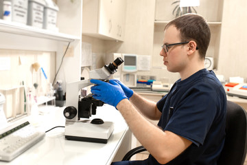 Laboratory assistant looking through microscope. Make research in laboratory. Science and medicine concept