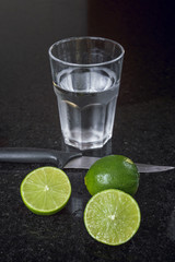A glass of water and lemons over a granite surface