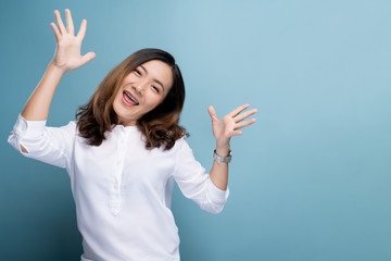 Happy woman make winning gesture isolated over blue background