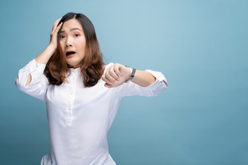 Fototapeta premium Shocked woman holding hand with wrist watch isolated on a blue background