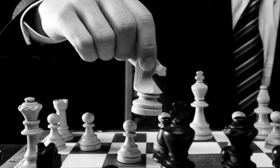 Business man playing chess - checkmate. Close-up chess pieces