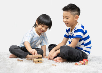 Fototapeta premium Children play with a toy designer on the floor of the children's room. Two kids playing with colorful blocks. Kindergarten educational games.