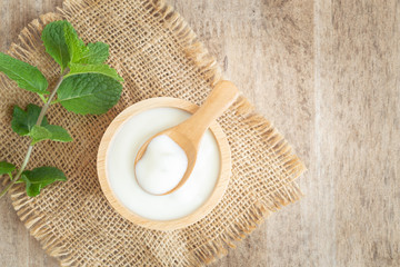 top view of natural greek yogurt in cup on old wooden table background. Yogurt is delicious tasty and healthy.