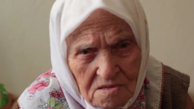 Close-up face of sad old woman. Elderly senior woman talking