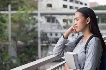 portrait of stressed, serious, pensive, thoughtful asian woman college student thinking in city campus environment