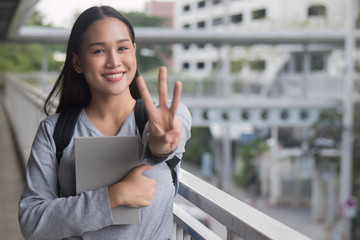 portrait of happy smiling asian woman college student pointing up 3 fingers, three points pose;...