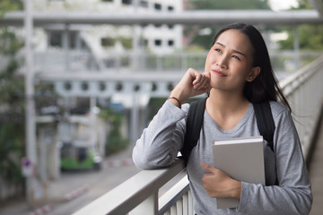 Fototapeta premium portrait of thoughtful asian woman college student thinking and looking up at possible education future, city campus environment