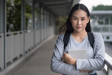 portrait of confident, smart asian woman college student, holding education textbook in city campus environment