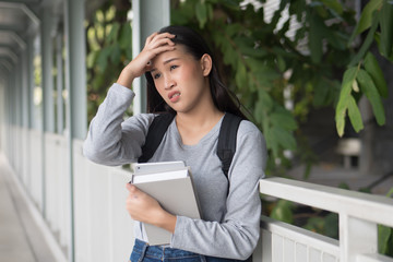 Fototapeta premium portrait of stressed, serious, worried, upset asian woman college student suffering from headache, cold in city campus environment
