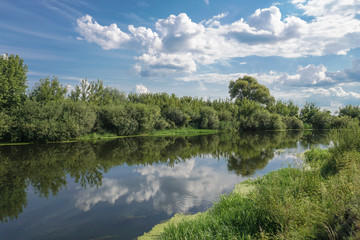Beautiful summer landscape with pretty river and colorful trees. View of the sky with beautiful clouds. Stock photo