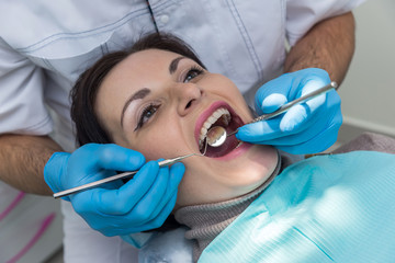 Doctor examining patient's teeth with mirror in dentistry