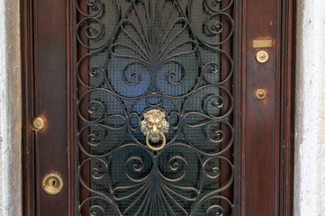 Closed wooden door with cast iron frame and metal door knocker