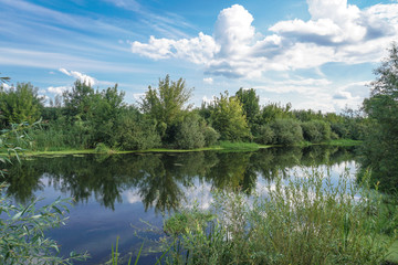 Obraz premium Beautiful summer landscape with pretty river and colorful trees. View of the sky with beautiful clouds. Stock photo