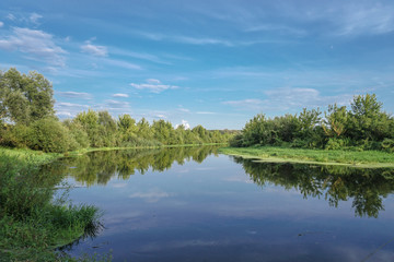 Beautiful summer landscape with pretty river and colorful trees. View of the sky with beautiful clouds. Stock photo