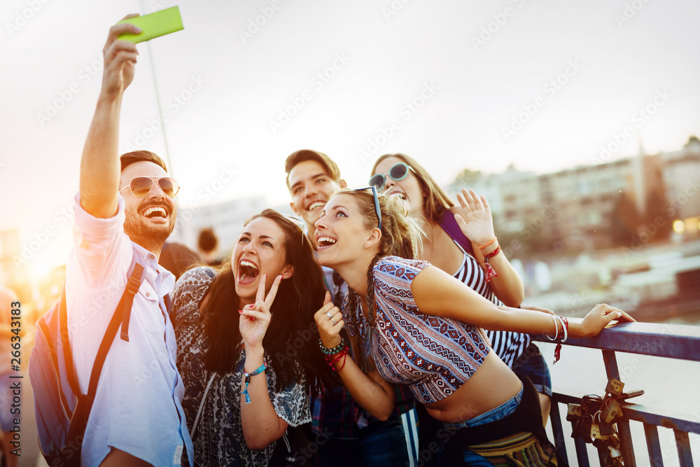 Wall mural happy young friends taking selfie on street