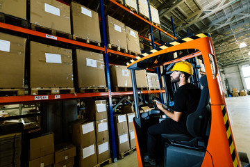 Warehouse worker doing logistics work with forklift loader