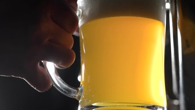 Below shot of a brewery worker pouring freshly-crafted beed in a glass to test the quality.