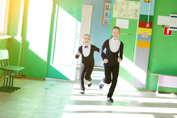 Fototapeta na wymiar Schoolgirls play around running down the hall. Girls students have fun running together playing at a school break